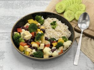Tofu s brokolicou, karfiolom, žltou a červenou paprikou, červenými fazuľkami servítované s ryžou na čiernom hlbokom tanieri so zlatým okrajom. Recept z NFI protokolu.