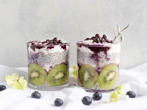 Chia pudding topped with fresh raspberries and a mint leaf, served in a glass jar on a wooden table.